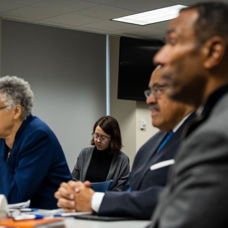 Five individuals pictured at a public meeting