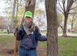A volunteer tree planter smiling next to a mature tree in Philadelphia