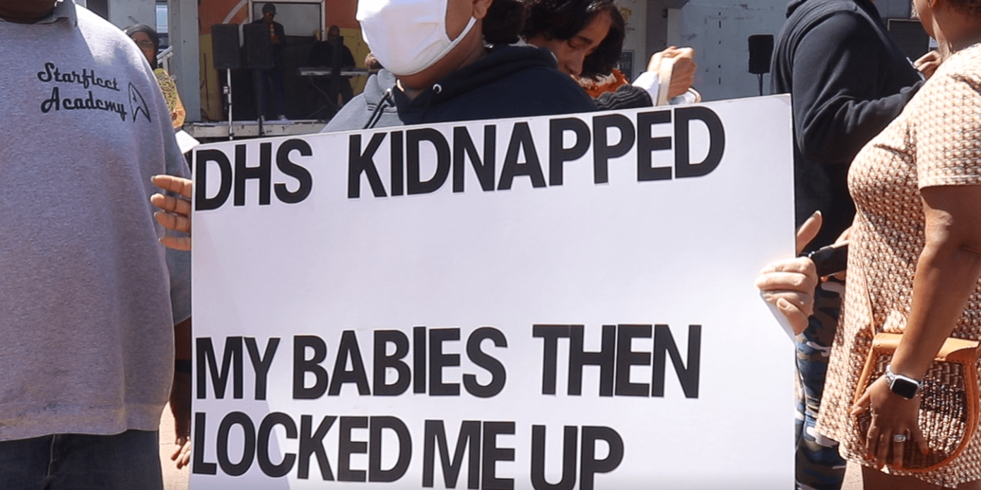 Protesters carry a sign at a May 2022 protest at LOVE Park after City Council released a scathing reports on the Department of Human Services’ lapses in caring for children. (Josh Childs)