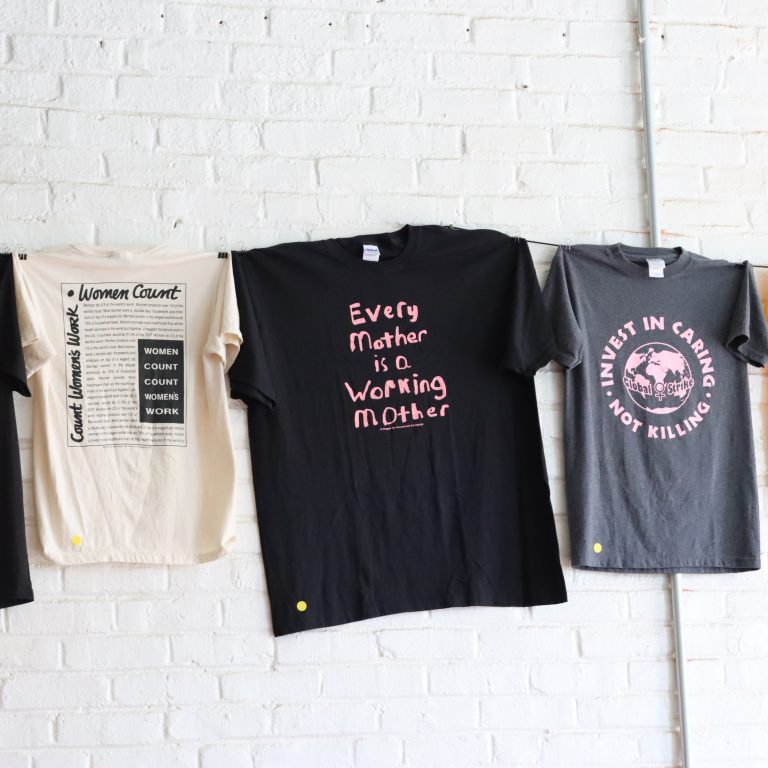 Shirts with messaging affirming wages for care work, which hang in the Crossroads Women’s Center on Wayne Avenue. (Photo: Rasheed Z. Ajamu)
