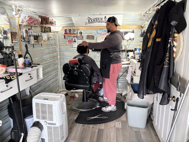 Siddiq, owner of Nicecutz Barber Truck cuts the hair of a customer.