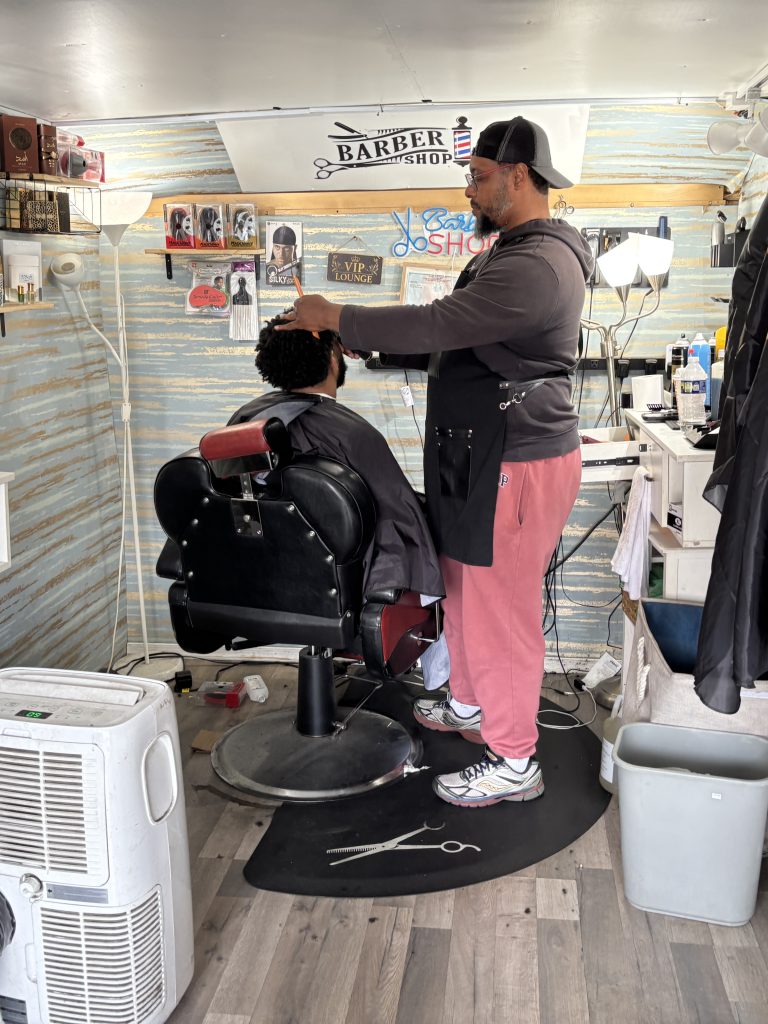 Siddiq, owner of Nicecutz Barber Truck cuts the hair of a customer.